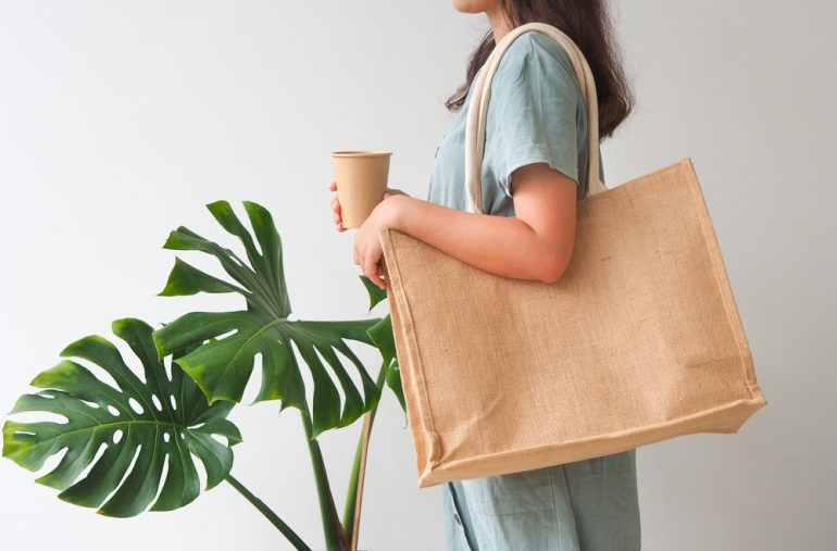 Woman holding jute bag or sack bag on white background. Reusable shopping bag. Natural material. Zero waste. Plastic free. Eco friendly concept.