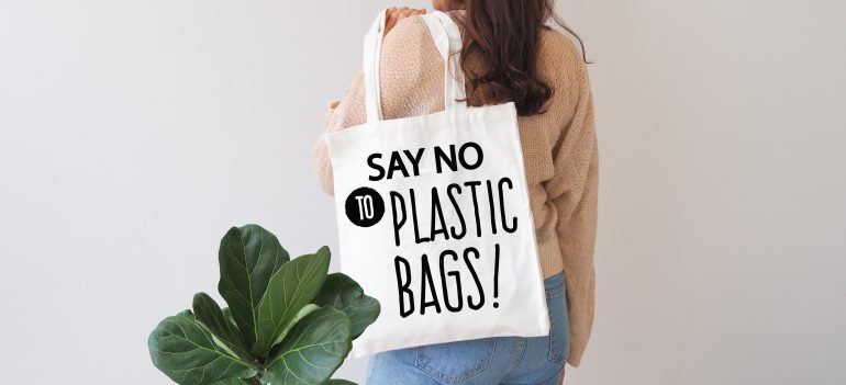 Woman holding canvas bag with a slogan stating "say no to plastic bags"